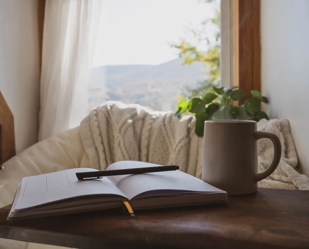 Woman journaling beside open Bible